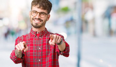 Genç yakışıklı adam gözlük izole üzerinde arka plan size işaret ve parmaklar, olumlu ve neşeli gülümseyen kamerayla