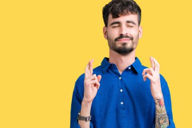 Yakışıklı delikanlı geçiş parmakları umut ve gözleri kapalı ile gülümseyen izole arka plan üzerinde. Şans ve batıl kavramı.