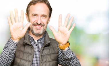 Kış Yelek gösterme ve parmakları ile işaret giyen orta yaş yakışıklı adam kendinden emin ve mutlu gülümseyerek süre on numara.