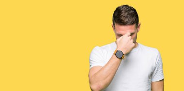 Casual beyaz t-shirt yorgun sürtünme burun ve göz yorgunluğu ve baş ağrısı duygu giyen yakışıklı adam. Stres ve hayal kırıklığı kavramı.