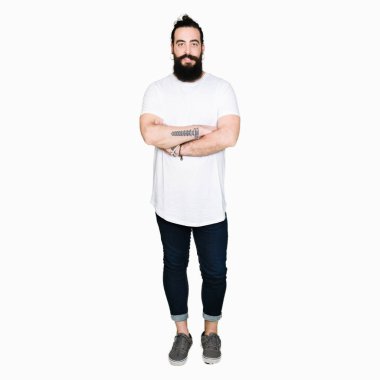 Uzun saç ve sakal ile gülümseyen casual beyaz t-shirt mutlu yüz giyen genç hipster adamla silah kameraya bakarak geçti. Olumlu bir kişi.