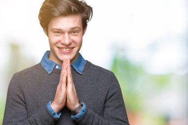 İzole arka plan üzerinde genç yakışıklı zarif adam el ile birlikte AF gülümseyen güven isteyen dua.