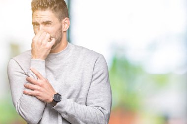 Kazak bir şey pis ve iğrenç kokulu izole arka plan üzerinde dayanılmaz koku, holding nefes parmak ile burun üzerinde giyen genç yakışıklı adam. Kötü kokuyor kavramı.