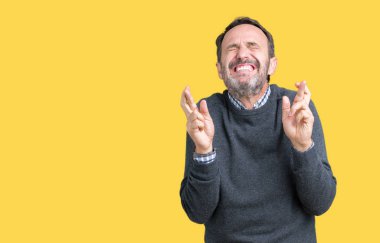 Yakışıklı orta yaş komuta sizde umut ve gözleri kapalı geçiş parmaklarıyla gülümseyen izole arka plan üzerinde bir kazak giyiyor. Şans ve batıl kavramı.