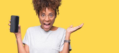 Smartphone ekran üzerinde gösterilen genç Afro-Amerikan kadın büyük gülümseme ile çığlık zaferini kutluyor ve ellerini kaldırdı arka plan çok mutlu ve heyecanlı, kazanan ifade izole