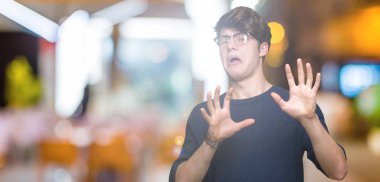 Şokta bağırarak korkuyor ve dehşet korku ifade dur hareketi el ile ile izole arka plan üzerinde gözlük takan yakışıklı delikanlı. Panik kavramı.