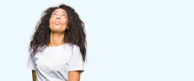 Casual beyaz t-shirt yapma balık yüz dudaklı, çılgın ve komik bir jest giyen kıvırcık saçlı Genç güzel kız. Komik ifade.