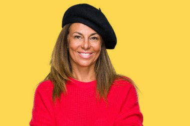 Moda bere üzerinde giyen orta yaş yetişkin kadın mutlu yüz ile gülümseyerek kameraya seyir silah geçti arka plan izole. Olumlu bir kişi.