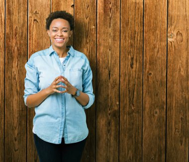 İzole arka plan el ele tutusun genç güzel Afrikalı-Amerikalı kadın ve rahat ve neşeli gülümseyen parmak çarpı işareti. Başarı ve iyimser