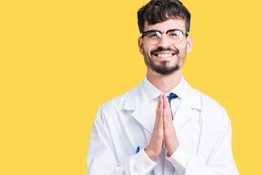 Ellerle birlikte AF emin gülümseyen için soran dua izole arka plan üzerinde beyaz önlük giyen genç profesyonel bilim adamı.