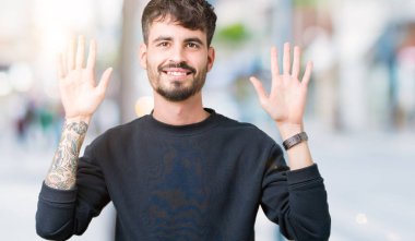 Yakışıklı delikanlı gösterilen ve parmakları ile işaret izole arka plan üzerinde kendinden emin ve mutlu gülümseyerek süre on numara.