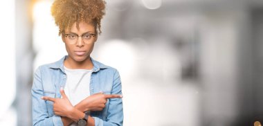 Güzel genç Afro-Amerikan kadın gözlük izole üzerinde işaretleme için her iki parmak, farklı yönde ile katılmıyorum arka plan