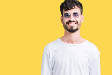 Genç yakışıklı adam yüzünde mutlu ve güzel bir gülümseme ile izole arka plan üzerinde güneş gözlüğü takıyor. Şanslı kişi.