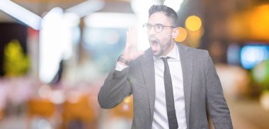 Genç yakışıklı iş adamı bağırarak ve ağzı üzerinde el ile yan için çığlık izole arka plan üzerinde. İletişim kavramı.