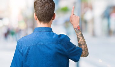 Genç yakışıklı adam gözlük izole üzerinden geriye doğru arkasında parmak eliyle işaret Posing arka plan