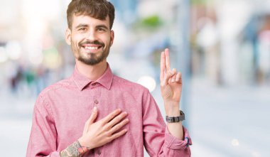 Pembe gömlek izole üzerinde giyen genç yakışıklı adam arka plan Swearing göğüs ve parmaklar, el ile bir sadakat sözü yemin yapma