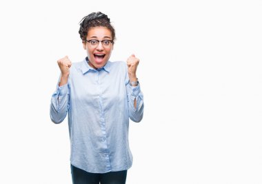 İzole arka plan üzerinde kutluyor gözlük takan genç örgülü saç Afro-Amerikan iş kız şaşırttı ve silah ile başarı için yükseltilmiş ve açık gözler hayrete düşürdü. Kazanan kavramı.