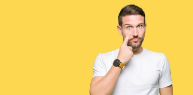 Casual beyaz t-shirt işaretleme göz izlerken seni jest, şüpheli ifade için giyen yakışıklı adam