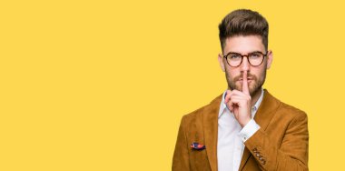 Dudaklarında parmak ile sessiz olmanı gözlüklü genç yakışıklı iş adamı. Sessizlik ve gizli kavramı.