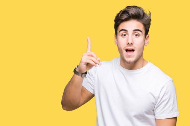 Başarılı fikirle izole arka plan işaret parmağı üzerinde beyaz t-shirt giyen genç yakışıklı adam. Çıktıktan ve mutlu. Bir numara.