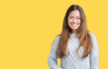 Yüzünde mutlu ve güzel bir gülümseme ile izole arka plan üzerinde kazak giyen genç güzel esmer kadın. Şanslı kişi.