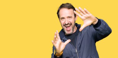 Orta yaş yakışıklı adam bir ceket giymiş el avuç içi ve parmaklar, kamera perspektifi kullanarak çerçeve yapıyor gülümseyen