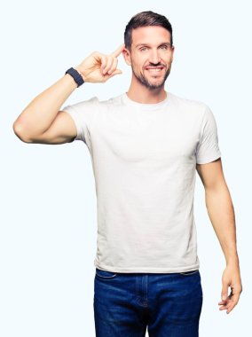 Casual beyaz t-shirt gülen bir parmak, harika bir fikir ya da düşünce, iyi hafıza ile baş gösteren giyen yakışıklı adam