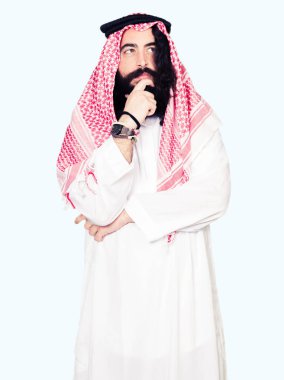 Geleneksel keffiyeh el ile çene düşünme hakkında soru, dalgın ifade üzerine şal uzun saçlı Arap iş adamı. Düşünceli yüzüyle gülümsüyor. Şüphe kavramı.