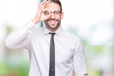 Gülümseyen, parmakları ile mutlu yüz üzerinden seyir göz el ile ok jest yapıyor izole arka plan üzerinde gözlük takan genç yakışıklı iş adamı.