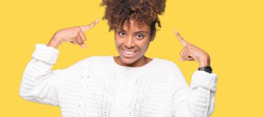 Güzel genç Afro-Amerikan kadın giyiyor kış kazak izole üzerinde arka plan hem el parmak, harika bir fikir ya da düşünce, iyi bellek ile baş gösteren gülümseyen