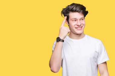 Casual beyaz t-shirt üzerinde izole giyen genç yakışıklı adam arka plan bir parmak, harika bir fikir ya da düşünce, iyi hafıza ile baş gösteren gülen