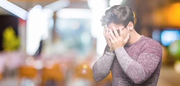 Young handsome man wearing glasses over isolated background with sad expression covering face with hands while crying. Depression concept.