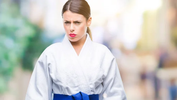 Young beautiful woman wearing karate kimono uniform over isolated background skeptic and nervous, frowning upset because of problem. Negative person.