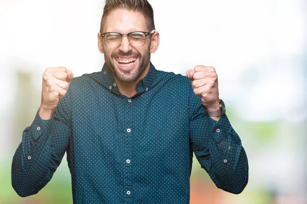 İzole arka kolları olan başarı için heyecan üzerinde gözlük takan genç yakışıklı iş adamı zafer kutluyor gülümseyen kaldırdı. Kazanan kavramı.