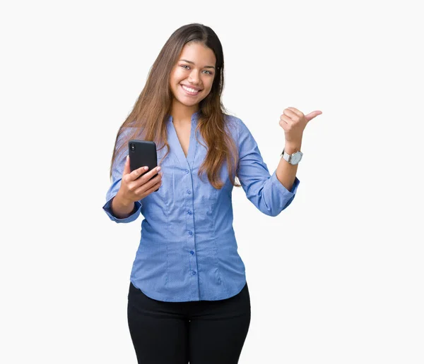 年轻美丽的黑发女商人使用智能手机在孤立的背景指向和显示与快乐的脸微笑的一侧 — 图库照片