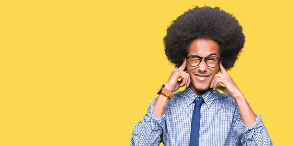 騒々しい音楽のノイズの腹式指で耳を覆ってメガネをかけてアフロの髪の若いアフリカ系アメリカ人ビジネスマン聴覚障害者の概念 — ストック写真