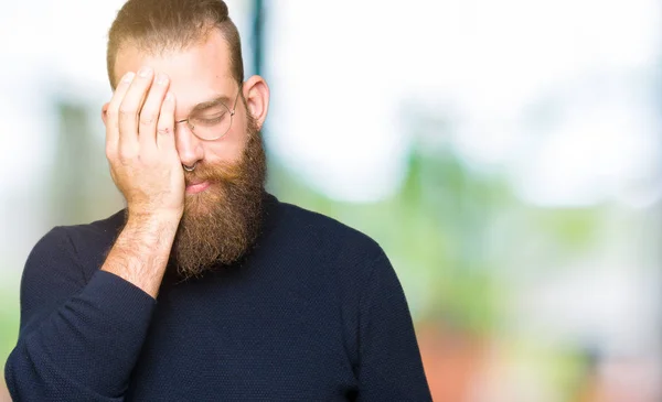 Young blond man wearing glasses and turtleneck sweater Yawning tired covering half face, eye and mouth with hand. Face hurts in pain.