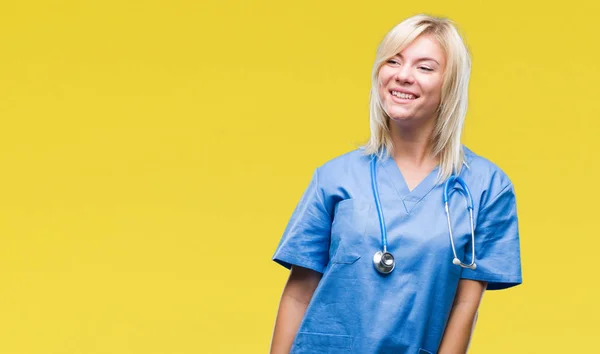 年轻美丽的金发碧眼的医生女士穿着医疗制服 在孤立的背景上看着一边面带微笑 自然表情 笑自信 — 图库照片