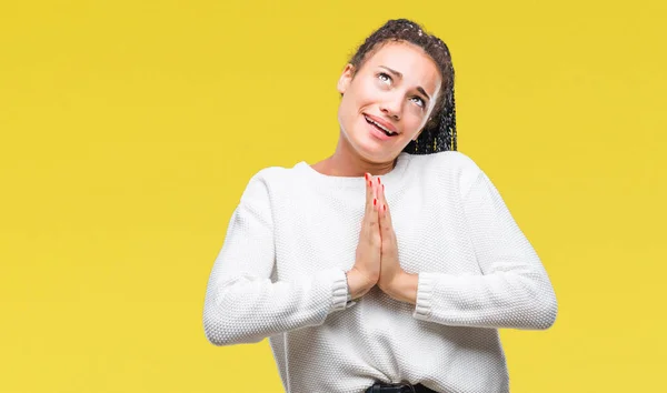 Young braided hair african american girl wearing winter sweater over isolated background begging and praying with hands together with hope expression on face very emotional and worried. Asking for forgiveness. Religion concept.