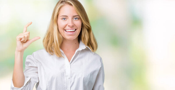 Красивая молодая деловая женщина на изолированном фоне улыбается и уверенно жестикулирует рукой, делая указатель размера пальцами при взгляде и камерой. Концепция измерения
.