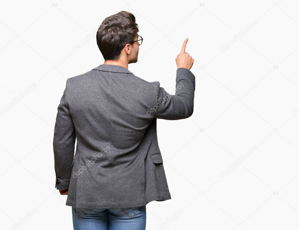 Young business man wearing glasses over isolated background Posing backwards pointing behind with finger hand
