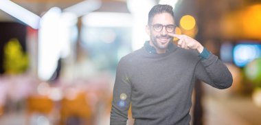Genç yakışıklı adam gözlük izole üzerinde işaretleme için yüz ve burun, neşeli gülümseyerek el parmak ile arka plan