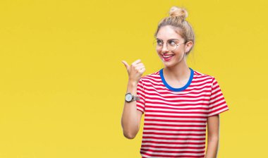 Seyir ve başparmak yanında yukarıyı mutlu yüz ile gülümseyen izole arka plan üzerinde gözlük takan genç güzel sarışın kadın.