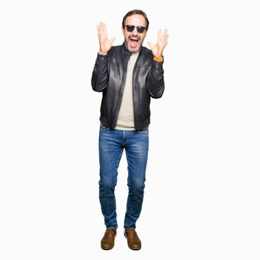 Orta yaş yakışıklı adam güneş gözlüğü ve siyah deri ceket giyen deli ve silah ile başarı için deli kutluyor ve kapalı gözleri heyecanlı çığlık kaldırdı. Kazanan kavramı