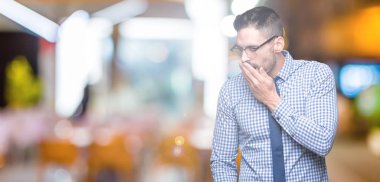 İzole arka plan üzerinde gözlüklü genç iş adamı esneme yorgun kapsayan ağız el ile sıkılmış. Restless ve uyku hali.