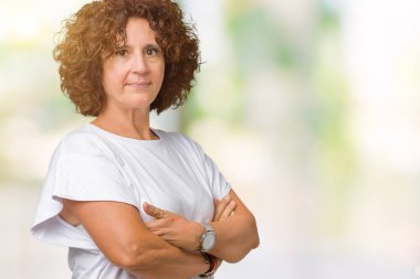 Üzerinde beyaz t-shirt giyen güzel orta ager üst düzey kadın arka plan gevşek yüzünde ciddi bir ifade ile izole. Basit ve çapraz silah ile doğal