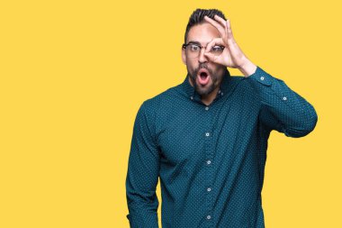 Sürpriz yüz, göz parmaklarının arasından seyir ile ok jest yapıyor izole arka plan üzerinde gözlüklü genç yakışıklı iş adamı şok. İmansız ifade.