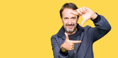 Orta yaş yakışıklı adam, mutlu yüz ile eller ve parmaklar ile çerçeve yapma gülümseyen bir ceket giyiyor. Yaratıcılık ve Fotoğrafçılık konsepti.