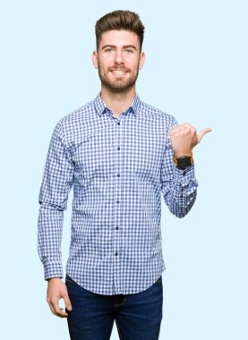 Genç yakışıklı Bussines adam mutlu yüz görünümlü ve başparmak yukarı ile yan işaret gülümseyen.