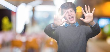 Genç yakışıklı zarif adam gösterilen ve parmakları ile işaret izole arka plan üzerinde kendinden emin ve mutlu gülümseyerek süre sekiz numara.